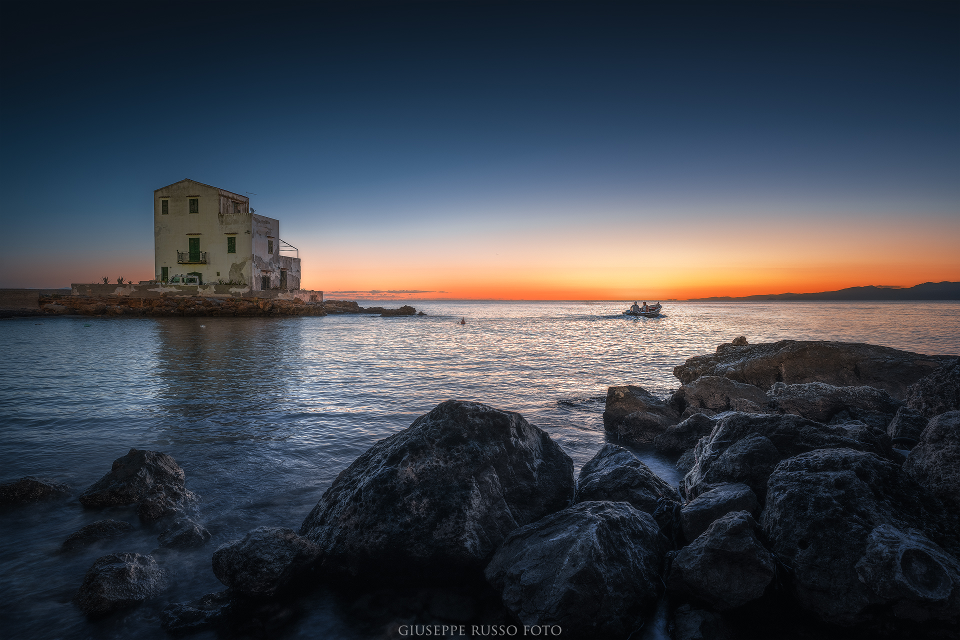 Luce dorata e barca di pescatori davanti alla costa siciliana